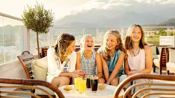 Lapsiporukka naureskelevat hotellit terassilla.