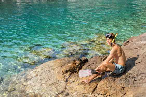 Poika istumassa kalliolla