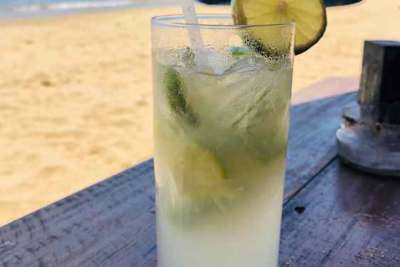 Drinkkilasi pöydällä, taustalla hiekkarantaa