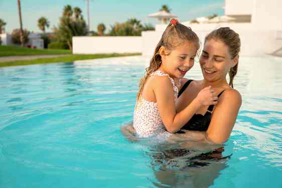 Äiti tytär sylissään uima-altaassa