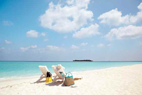 Kaksi aurinkotulia valkoisellarantahiekalla Malediiveilla.