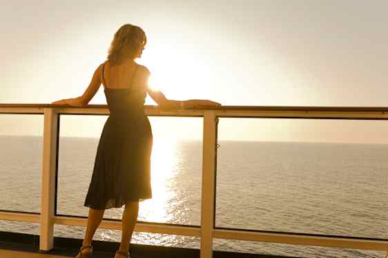 Nainen ihailee auringonlaskua risteilylaivan kannelta