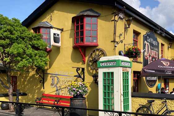 Keltainen talo, jossa on punaiset ikkunanpuitteet. Edessä on valkoinen ja vihreä puhelinkoppi.