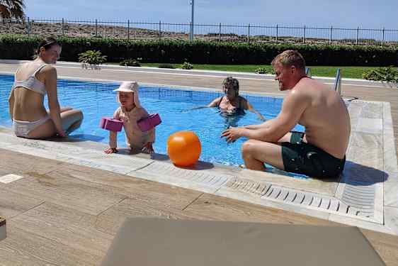 Vanhemmat ja isovanhemmat altaassa yhdessä pikkutytön kanssa.