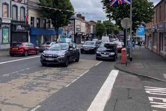 Katu, jossa on autoja ja lyhtypylväässä Ison-Britannian lippu.