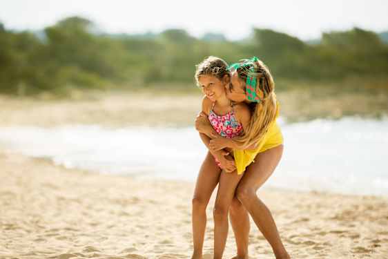 Kaksi tyttöä rannalla uimapuvuissa