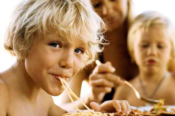 Vaaleahiuksinen poika syö spagettia