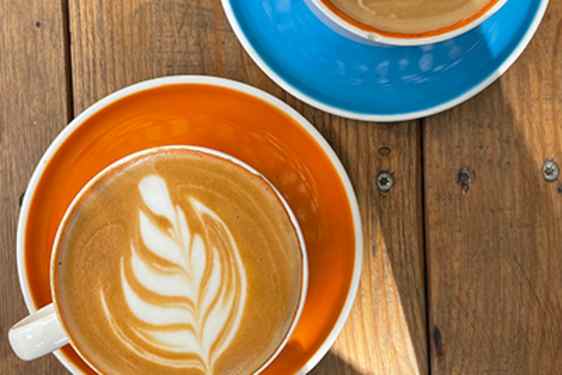 Kaksi kahvikuppia, joissa on koristettu maitovaahto