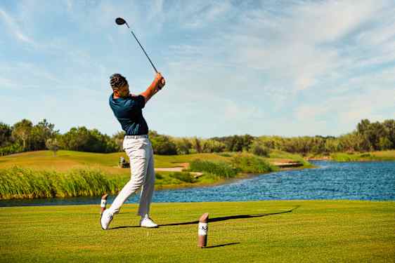 Mies lyömässä golfkentällä