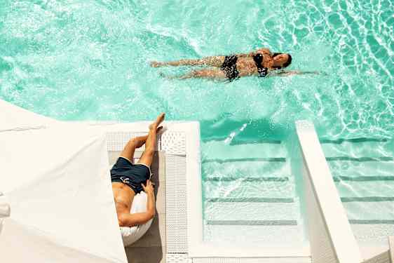 Terassi, jonka vieressä allas ja kaksi lomailijaa