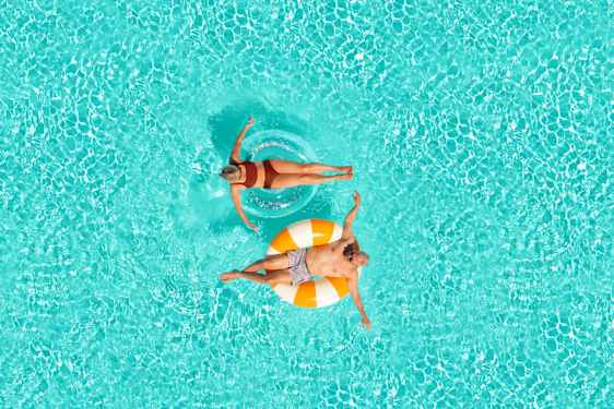 Mies ja nainen kellumassa uimarenkaissa