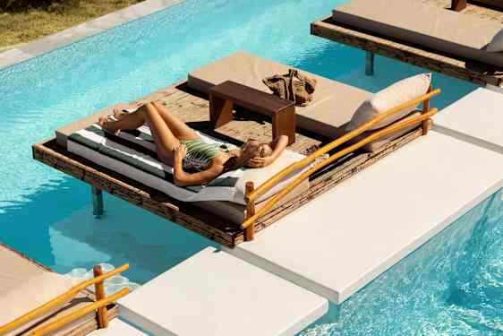 Aurinkopatjat ja nainen altaan reunalla