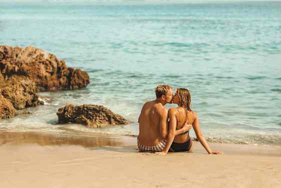 pari istumassa ja suutelemassa rannalla