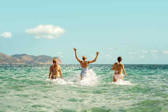 Kolme henkilöä roiskuttamassa vettä meressä