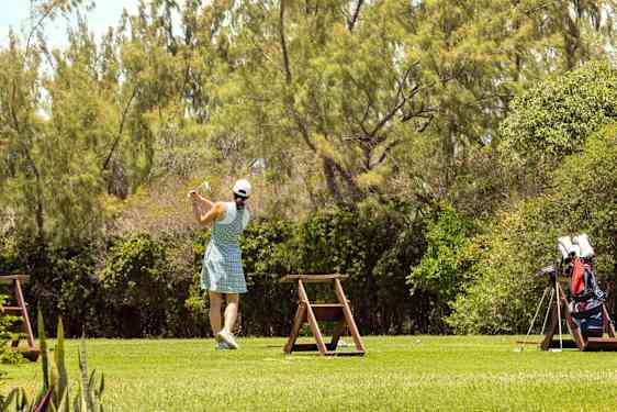Nainen lyömässä swingiä vehreällä golfkentällä