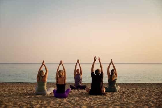 Grupp gör yoga på strand