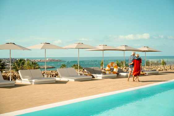 Mies ja nainen kävelemässä uima-altaan reunalla