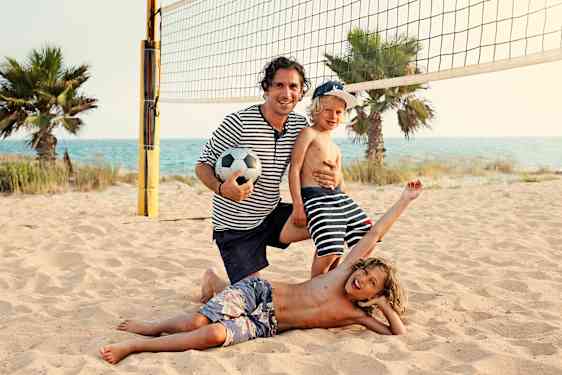 Perhe pelaamassa lentopalloa rannalla
