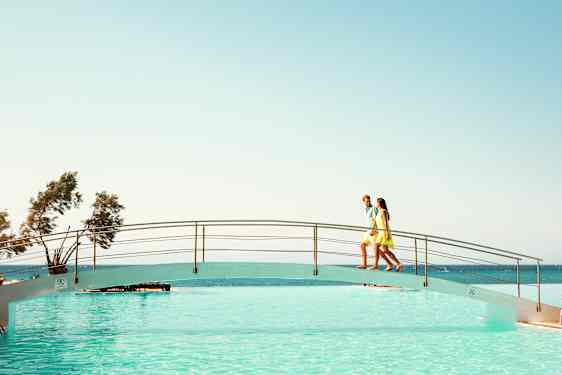 Mies ja nainen uima-altaan ylittävällä kävelysillalla