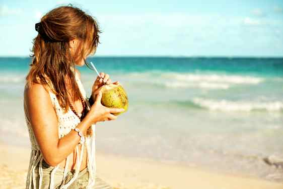 Nainen rannalla kookosdrinkin kanssa