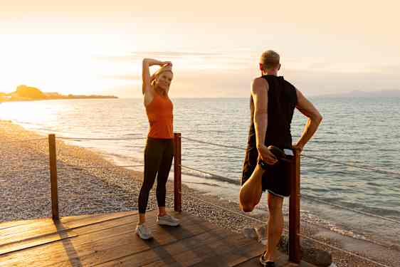 Pariskunta venyttelee rannalla - aktiivilomat Tjäreborgilta