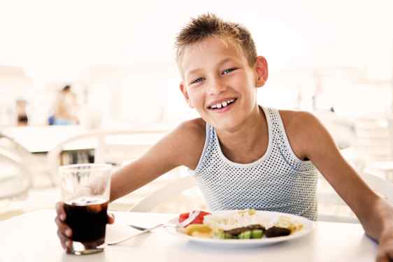 Hymyilvä poika ruokapöydässä