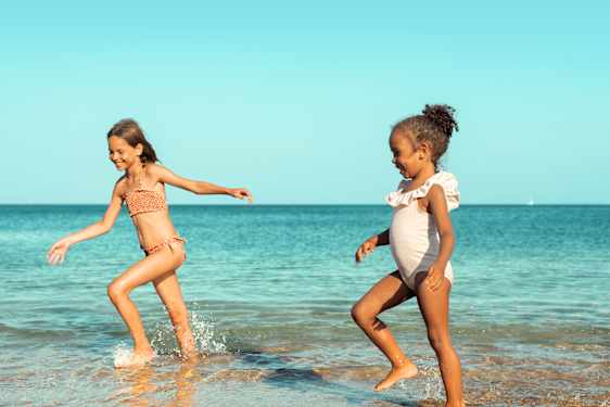 kaksi tyttöä juoksee uimaan rannalla Thaimaassa