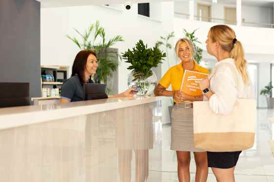 Opas, asiakas ja vastaanottovirkailija hotellin tiskillä