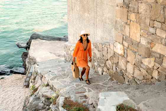 nainen kävelemässä rannalla sijaitsevan muurin edessä