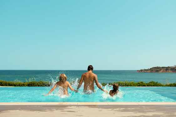 Perhe hyppää yhdessä uima-altaaseen