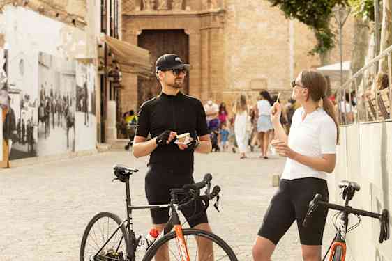 Kaksi henkilöä pitää taukoa pyöräretkellä ja syö jäätelöä