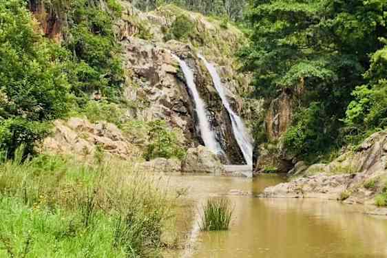 Vesiputous ja vehreää kasvillisuutta.