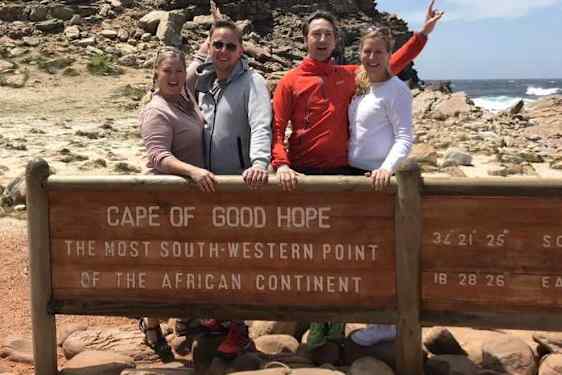 Artkkelin kirjoittaja matkaseuralaistensa kanssa kuvattuna Hyväntoivonniemen kyltin luona.