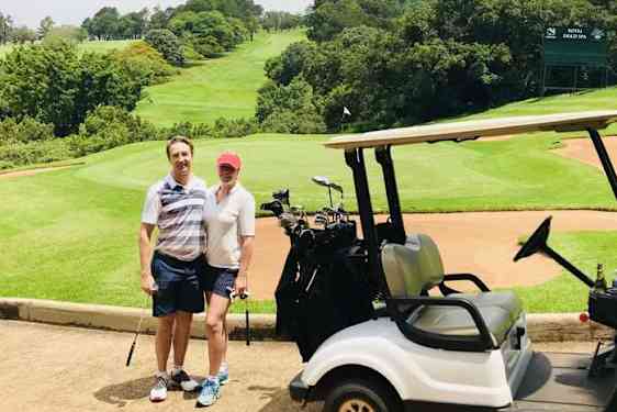 PARISKUNTA JA golfauto, taustalla vihreä golfkenttä