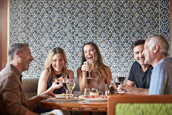 Viisihenkinen seurue ravintolan pöydässä syömässä