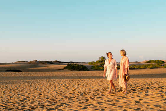 Kaksi naista kävelevät hietikolla