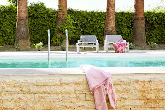 Uima-allas, kaksi aurinkotuolia ja vaalenapunainen pyyhe altaan reunalla.