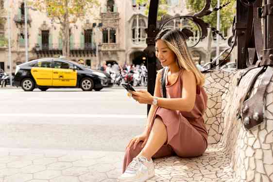 Nainen istuu puhelin kädessään