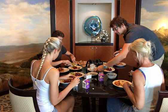 Nelihenkinen perhe aamiaispöydässä ravintolassa.