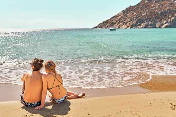 Mies ja nainen istumassa rantahiekalla