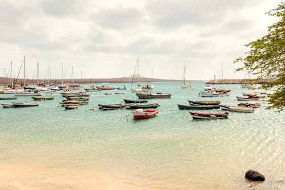 nainen joogaamassa rannalla auringon laskiessa