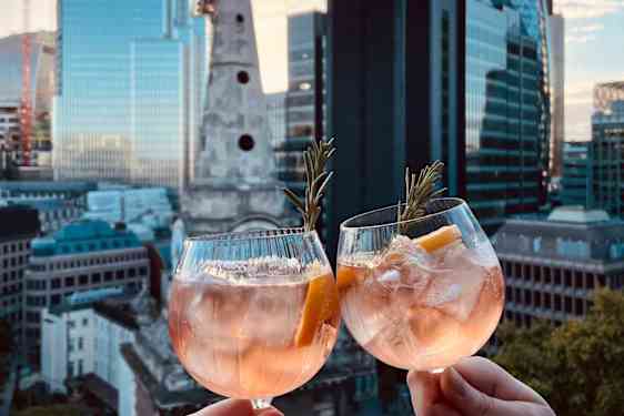 Drinkkilasit ja auringonlasku taustalla Lontoon kaupunkimaisemaa