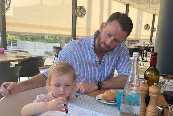 Pikkutyttö piirtää ja aikuinen seuraa sivusta