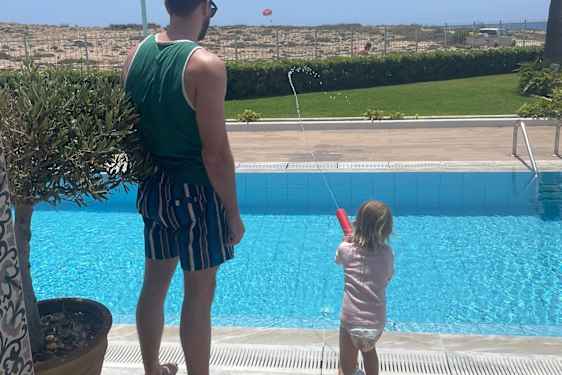 Eno ja pikkutyttö leikkivät vesipyssyllä.