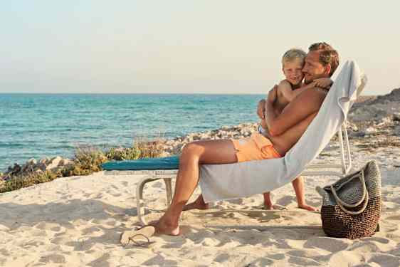 Mies ja lapsi aurinkotuolilla rannalla