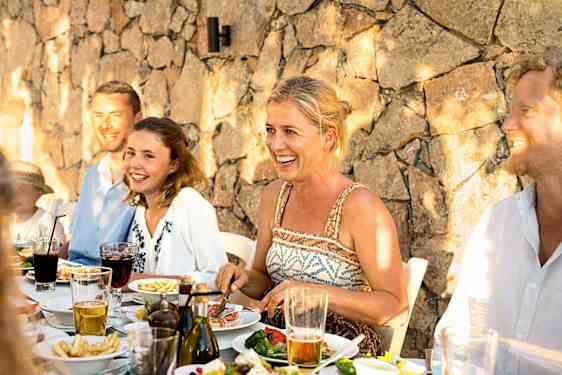 Gruppe af voksne og børn spiser mad sammen