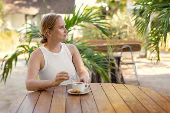 Nainen kahvittelemassa palmujen ympäröimänä