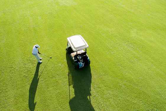 Golfauto ja pelaaja väylällä ylhäältä kuvattuna