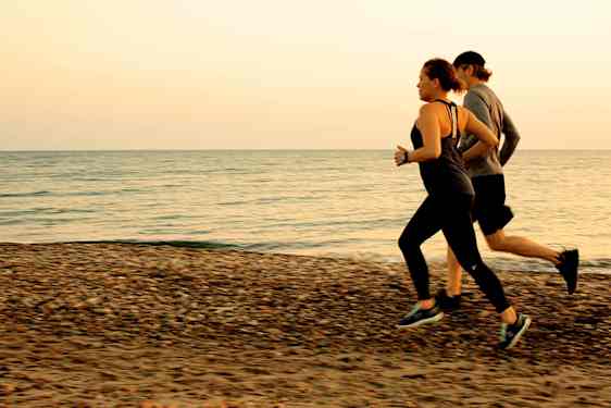Pariskunta juoksemassa rannalla