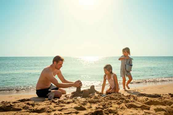Perhe leikkii rannalla.